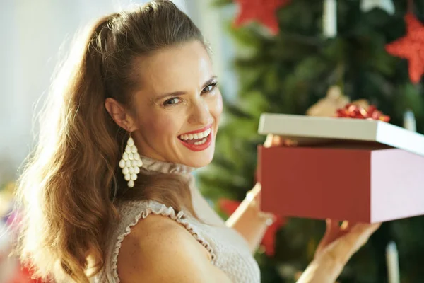 幸福的现代妇女的肖像附近圣诞树打开圣诞礼物盒 — 图库照片