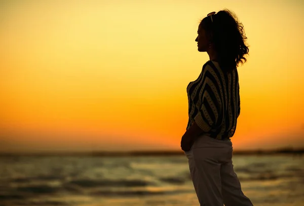 現代女性の距離に探して海岸に沈む夕日をお楽しみください — ストック写真