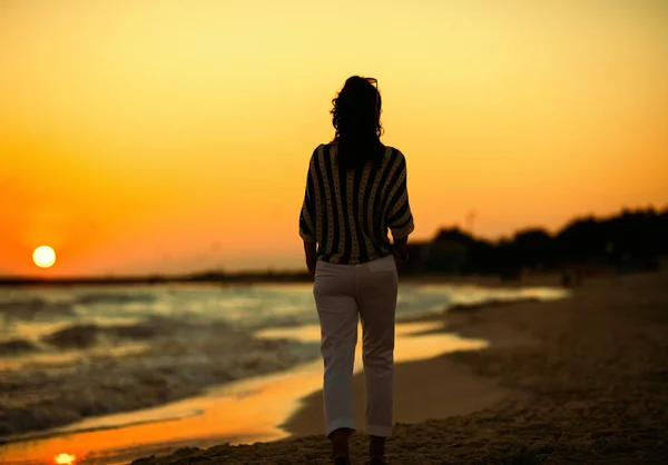 夜のビーチを歩いてスタイリッシュな女性の後ろから見て — ストック写真