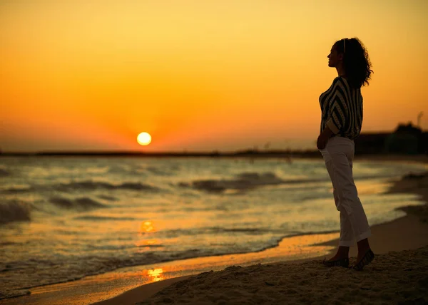 距離を探している現代女性の全長し 海岸に沈む夕日をお楽しみください — ストック写真