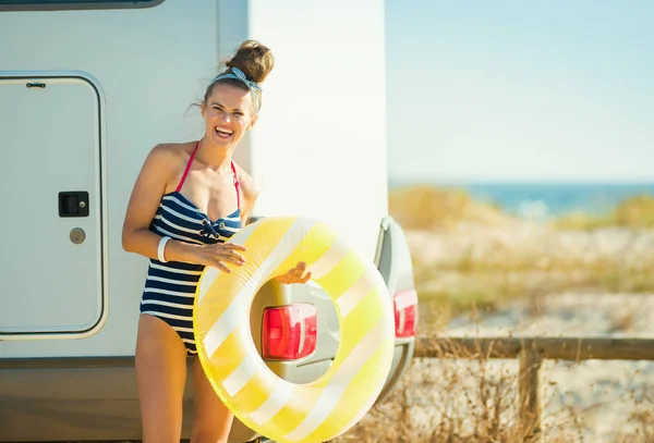 ビーチでトレーラーに近い黄色膨脹可能な救命浮環 ビーチウェアで笑顔のスタイリッシュな女性の肖像画 — ストック写真