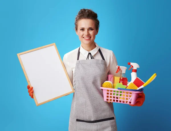 Happy Young Scrubwoman Apron Basket Cleansers Brushes Showing Blank Board — Stock Photo, Image