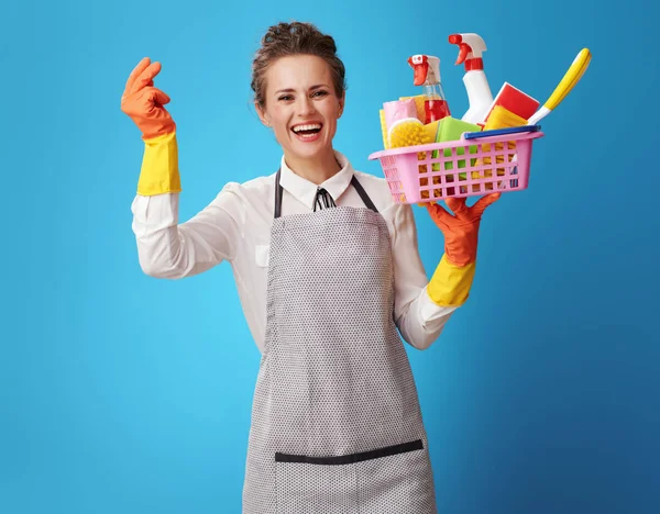Happy Young Scrubwoman Apron Basket Cleansers Brushes Fingers Snapping Blue — Stock Photo, Image