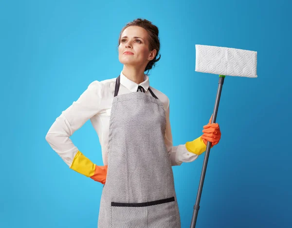 Trots Jonge Huishoudster Schort Met Een Mop Tegen Blauwe Achtergrond — Stockfoto