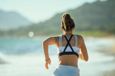 Aktif kadın jogger spor giysileri okyanus kıyısında arkasından çalışan akşam gördün. Okyanus ve akşam yaz esintisi spor için kentsel hustle üzerinden çalıştırmak için mükemmel sesler