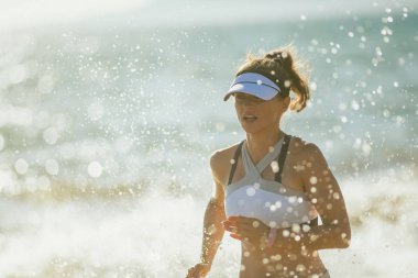 deniz kıyısı akşam çalışan üzerinde fitness giysili genç kadın koşucu. aynı egzersiz rutin doluyor. bir şey 30 yaşında kadın güzel deniz kıyısı egzersiz çalıştıran sahip