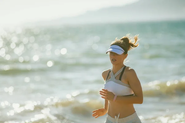 スポーツ服に海の海岸で夕方には実行しているスポーツ女性に合います 世界的に人気のあるジョギングは海の海岸地形と風の抵抗は常に変化のために困難になります — ストック写真