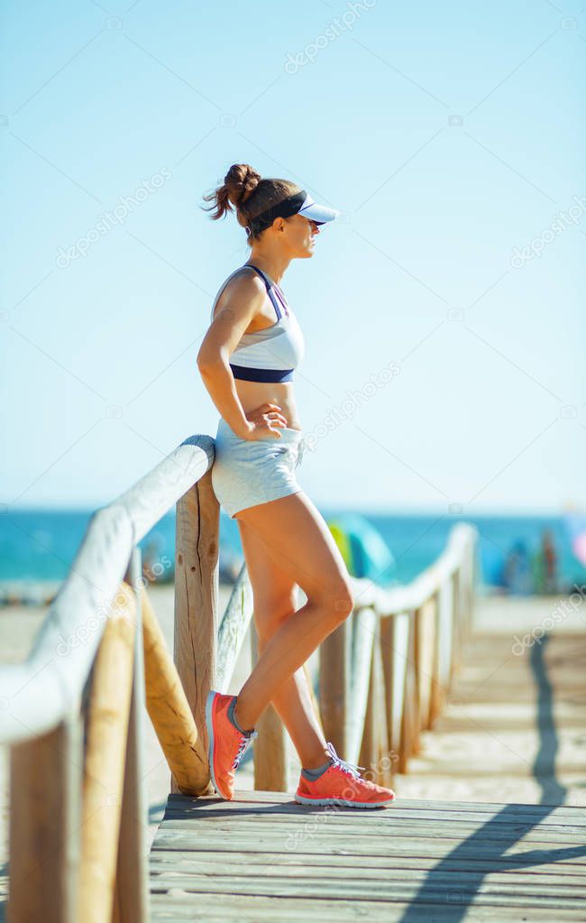 young woman jogger in sport clothes on the seashore looking into the distance. exercise improves not only your health but also your mood. workout on the seashore even more calming and stress relieving