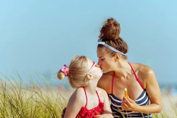 Smiling Modern Mother Child Swimwear Holding Lipstick Spf Kissing Ocean — Stock Photo, Image