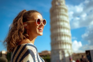 mutlu genç kadın güneş gözlüğü ve çizgili bluz leaning tower Pisa, İtalya karşı mesafe içine arıyorum. Güneşli yaz öğle. iyi touristed yolunu biliyorum. mikro tatil sahip. Avrupa kadın