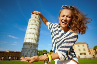 gülümseyen çizgili bluz leaning tower Pisa, İtalya karşı seyahat etmek fotoğraf için poz olarak şık kadın. Burada Im ve klişeleşmiş turist fotoğraf çekmek gerekir. Mikro Seyahat sahip. beyaz kadın. 