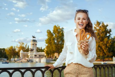 beyaz gömlek ve şort ile geleneksel İspanya churro Buen Retiro Park Madrid, İspanya şık kadın gülümsüyor. churro - klasik İspanyol tatlı tedavi. Mavi gökyüzü. Güneşli yaz evening.solo Gezgin