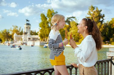 mutlu son moda anne ve kızı gezginler ile El Retiro Park Madrid, İspanya birbirlerine bakarak geleneksel İspanya churro. churro - klasik Madrid tatlı snack. Güneşli yaz akşam.