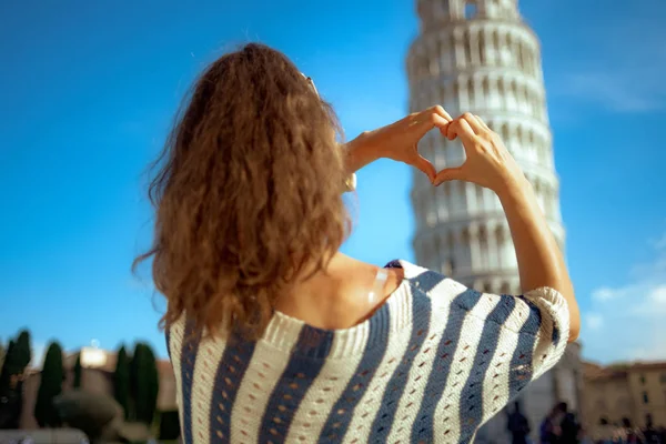 イタリア ピサの斜塔にハート形の手を示すストライプ ブラウスの若い女性の後ろから見られます マイクロの休日を持っています ここで群衆を避けることはできません 青い空 日当たりの良い夏の正午 — ストック写真