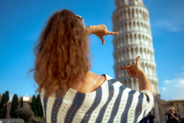 在意大利比萨 从现代女人身后穿条纹衬衫框架 双手靠在倾斜的塔楼上 有微行程 过度旅游的典型例子 阳光明媚的夏季正午 — 图库照片
