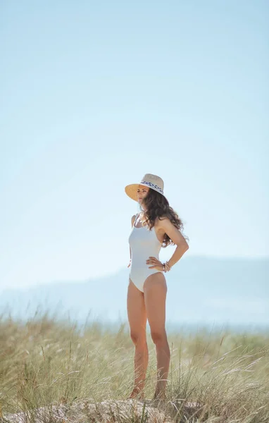 距離を探して海岸に白いビーチウェアの現代の女性の完全な長さの肖像画 女性は日焼け防止のための麦わら帽子を身に着けています 太陽は 髪を保護します 青い空 白人女性 — ストック写真