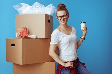 Modern karton kutu yakınındaki beyaz tişört içinde izole mavi kahve fincanı ile gülümseyen. profesyonel Nakliyeciler tehcir stressiz tutmak.