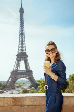 Mavi Jeans ile kahve Kupası Paris, Fransa'da Eyfel Kulesi önünde genel mutlu zarif kadın portresi.