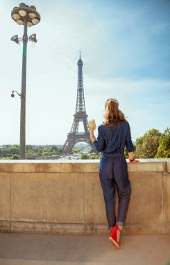 Mavi Jeans mutlu şık kadın portresi uzunluğu genel olarak Eyfel Kulesi Paris, Fransa'da karşı kahve Kupası ile dolu..