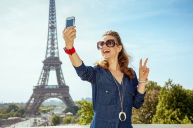 Mavi Jeans selfie cep telefonu ile alarak ve Trocadero Paris, Fransa'da Eyfel Kulesi manzaralı, zafer gösteren genel mutlu son moda kadın.