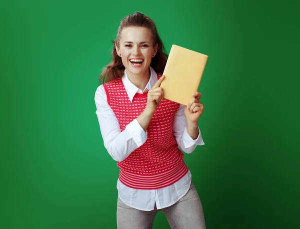 Estudante mostrando livro amarelo sobre quadro verde fundo — Fotografia de Stock
