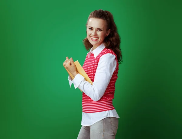 Happy learner woman holding yellow book on green background — Stock Photo, Image