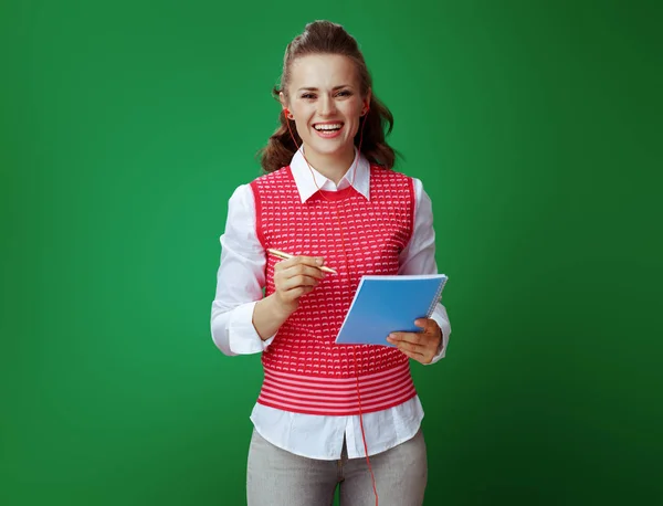 Frau mit Kopfhörer macht sich Notizen in blauem Notizbuch — Stockfoto