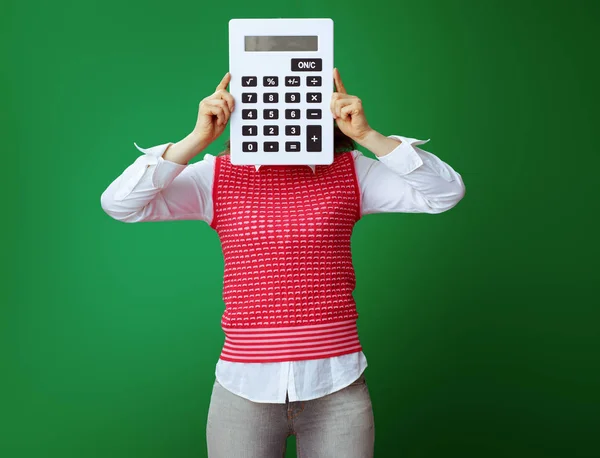 Student se schovává za velké bílé Kalkulačka izolované na zelené — Stock fotografie