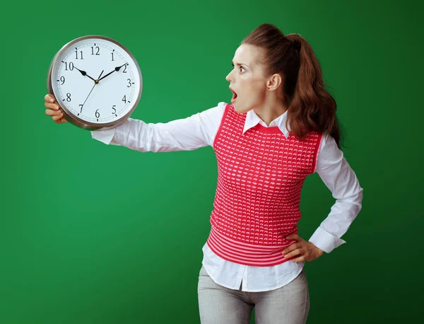 Leerling vrouw kijken naar witte ronde klok dat geïsoleerd op groen — Stockfoto