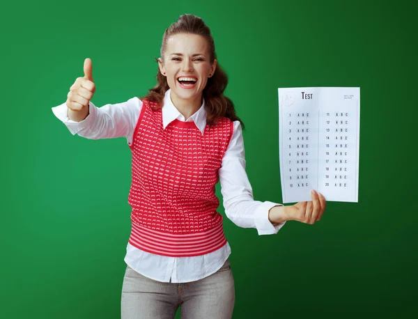 Smiling student showing A + exam result against green background — стоковое фото