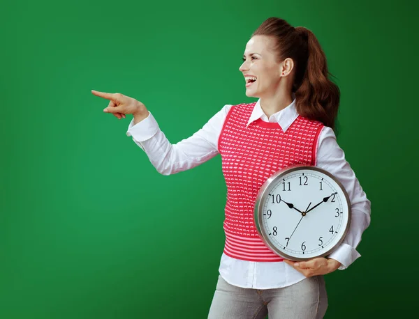 Student woman with white round clock pointing at something — Stock Photo, Image