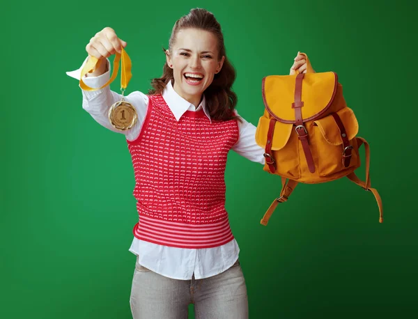 Studentka žena ukazuje číslo jedna zlaté medaile a žluté backpac — Stock fotografie