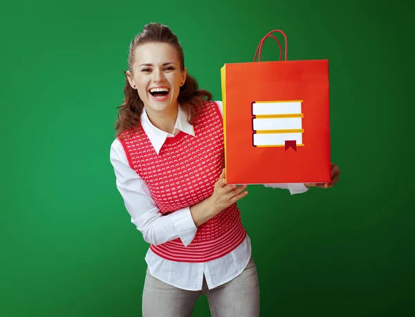 Souriant apprenant femme montrant sac à provisions rouge avec des livres — Photo