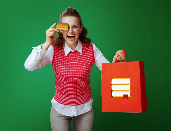 Student with red shopping bag with books holding gold credit car — Stock Photo, Image