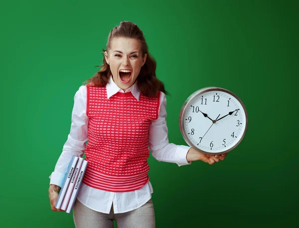 Сердита студентка з підручниками показує білий круглий годинник — стокове фото