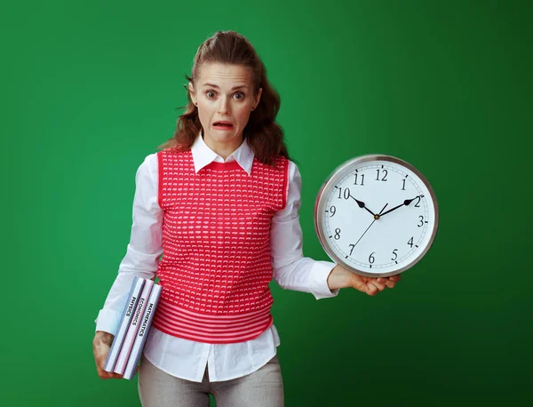 Geschokt fit leerling vrouw met schoolboeken en witte ronde klok — Stockfoto