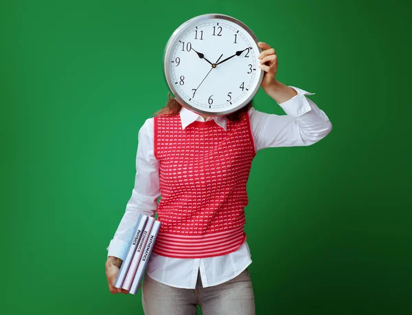 Estudiante en forma con libros de texto escondido detrás de reloj redondo blanco —  Fotos de Stock