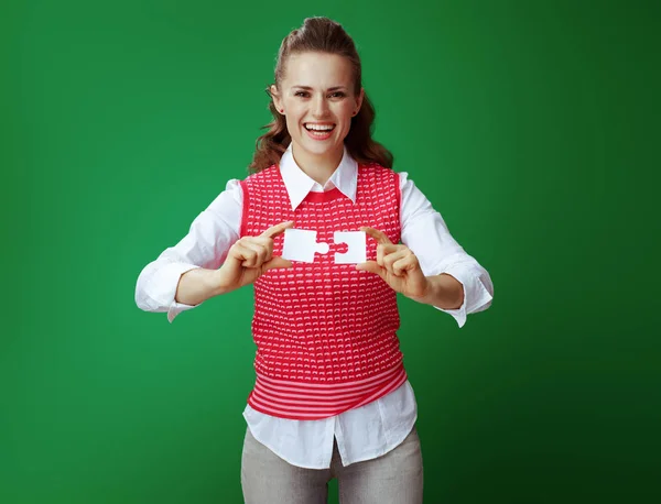 Studente donna assemblare 2 pezzi di puzzle su sfondo verde — Foto Stock