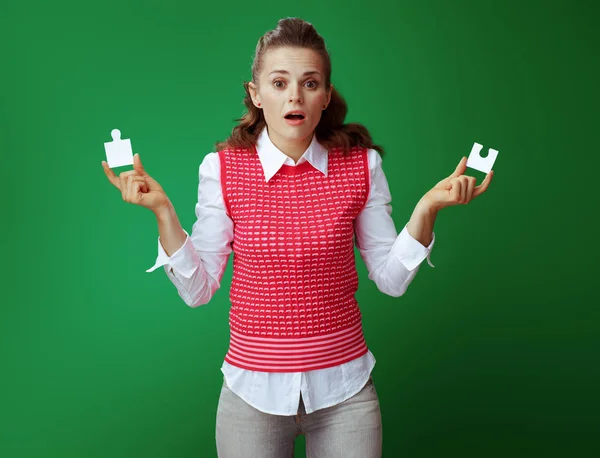 Mulher aprendiz com 2 peças de quebra-cabeça isolado em verde — Fotografia de Stock