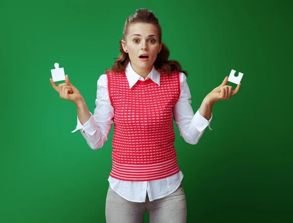 Learner woman with 2 pieces of puzzle isolated on green — Stock Photo, Image