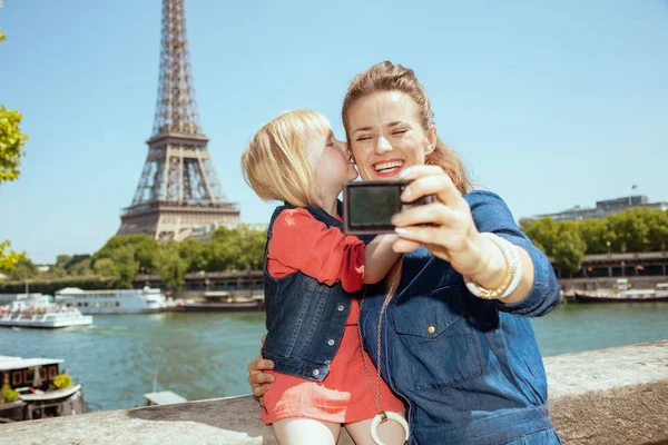 Modern anne ve çocuk turist Eyfel Kulesi Paris, Fransa'da çok uzak olmayan dijital fotoğraf makinesi ile selfie alarak gülümseyen.