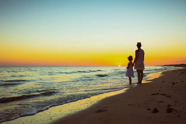 Madre e hija viajeros de pie en la orilla del mar al atardecer —  Fotos de Stock