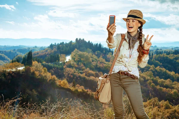 Turist kvinna tar selfie med telefon och visar seger gestu — Stockfoto