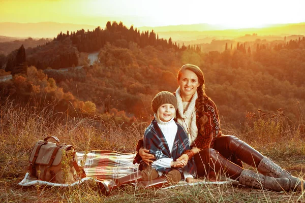 Sonrientes senderistas en forma de madre e hijo sentados en una manta —  Fotos de Stock