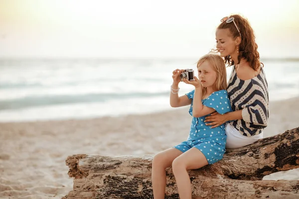 Moeder en dochter reizigers, zittend op een houten addertje onder het gras en taki — Stockfoto