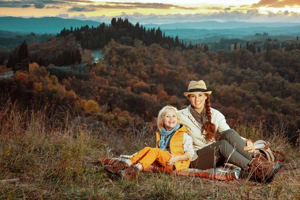 Lykkelig moderne mor og datter sidder på tæppe - Stock-foto