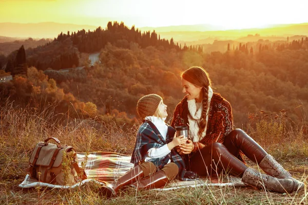 Mère et fille avec thermos tasse assis sur la couverture et regarder — Photo