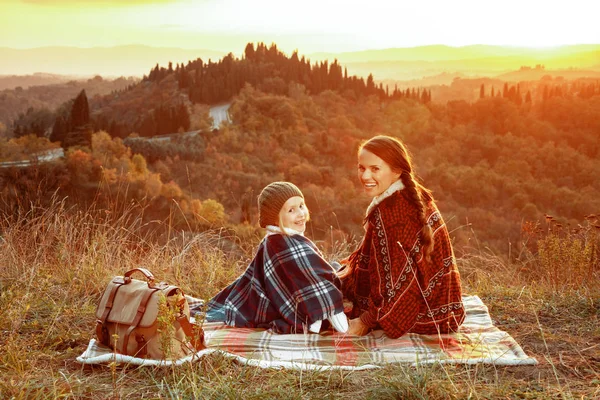 Madre e hijos excursionistas en Toscana en la puesta del sol sentado en la manta —  Fotos de Stock