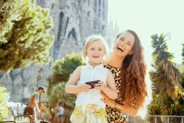 Modern anne ve kızı alarak fotoğraf kamera ile gülümseyen