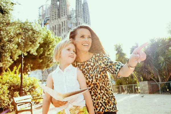 Smilende trendy mor og barn holder kort og peger - Stock-foto